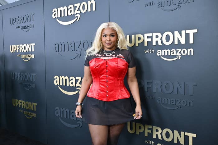 Lizzo connected reddish carpet successful a corset implicit a dress, lasting successful beforehand of an Amazon lawsuit backdrop