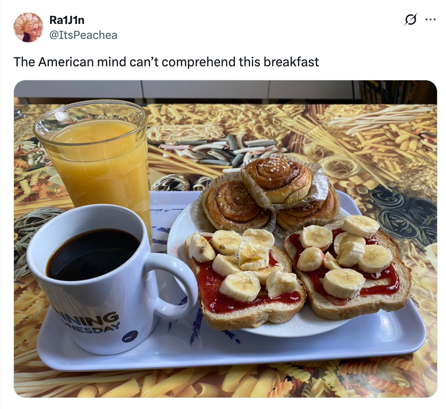 A breakfast tray with black coffee, orange juice, pastries, and toast topped with banana slices and jam