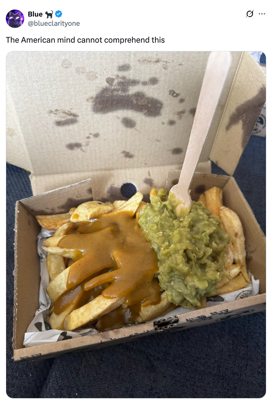 Box of fries with curry sauce and mushy peas, accompanied by a wooden fork. Tweet text suggests cultural novelty