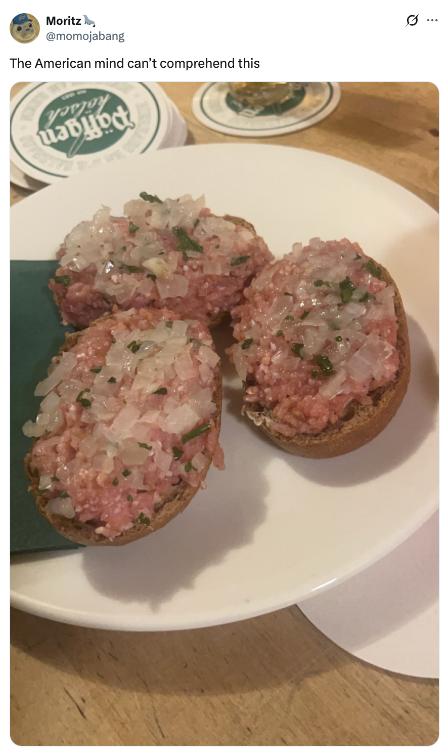 Three pieces of bread topped with raw minced meat, diced onions, and herbs on a plate