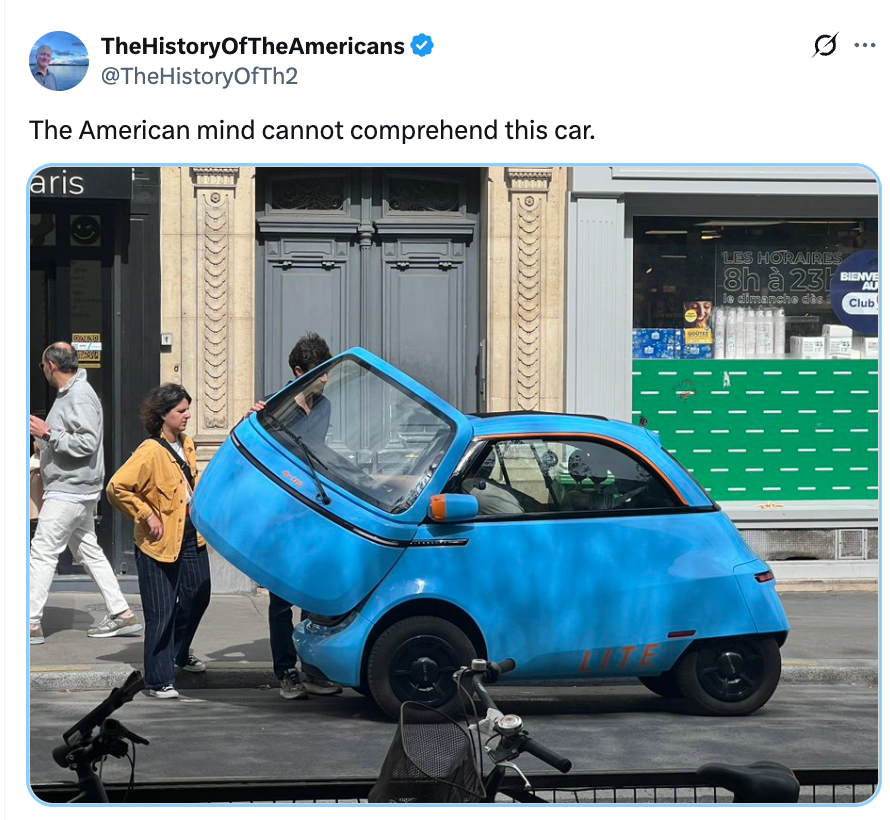 People on a sidewalk notice a very small, uniquely designed car with an open front entrance