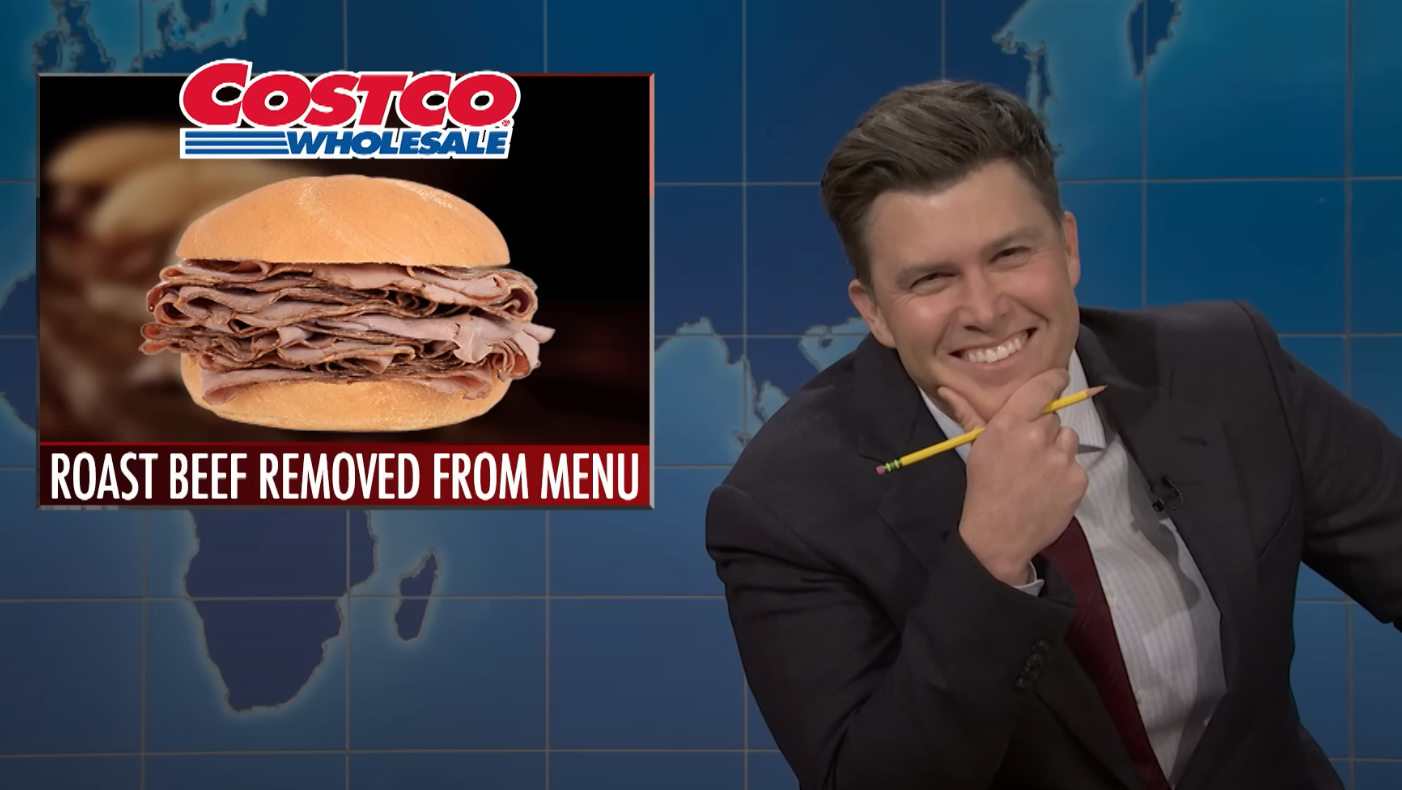 Person on a news set smiles while holding a pencil. A graphic shows a Costco roast beef sandwich with text: "Roast Beef Removed from Menu."