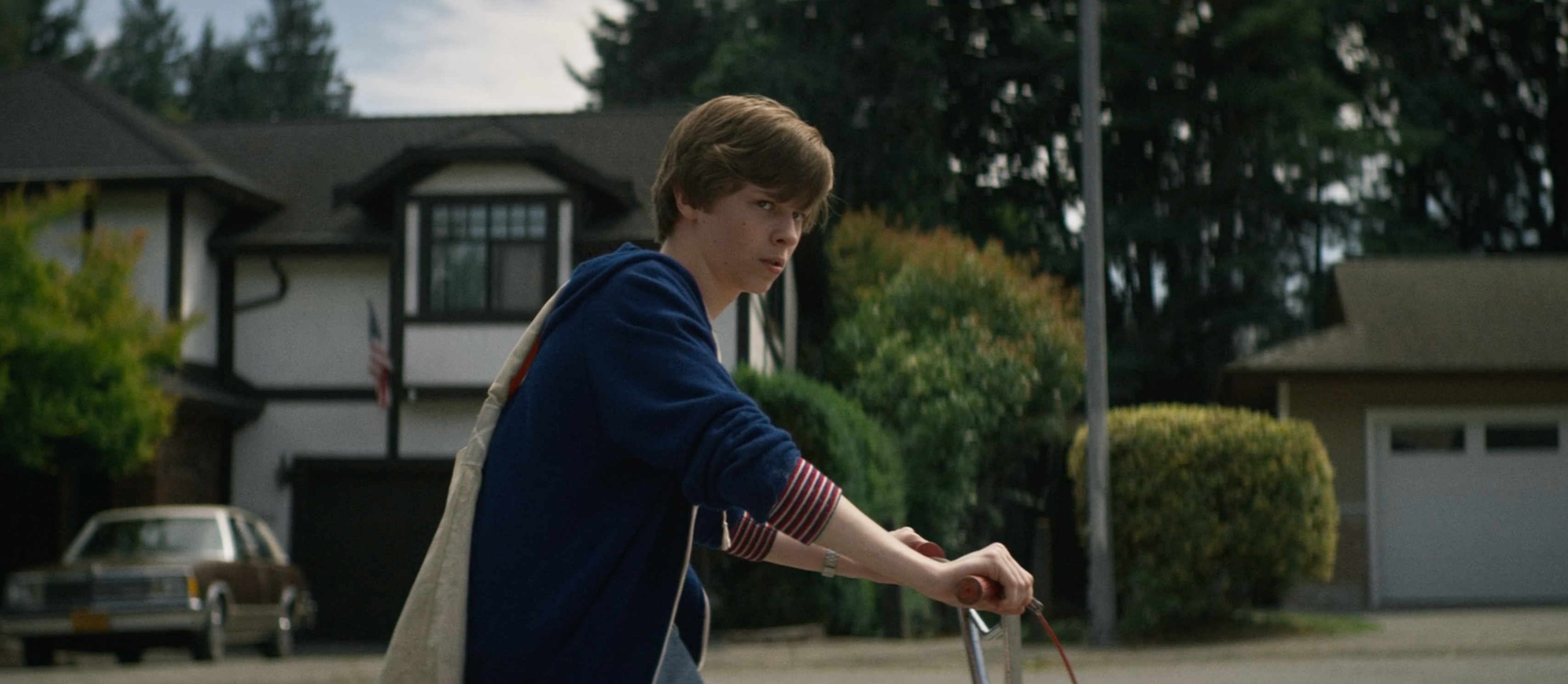 Boy riding a bike in a suburban neighborhood in a scene from &quot;Summer of '84&quot;