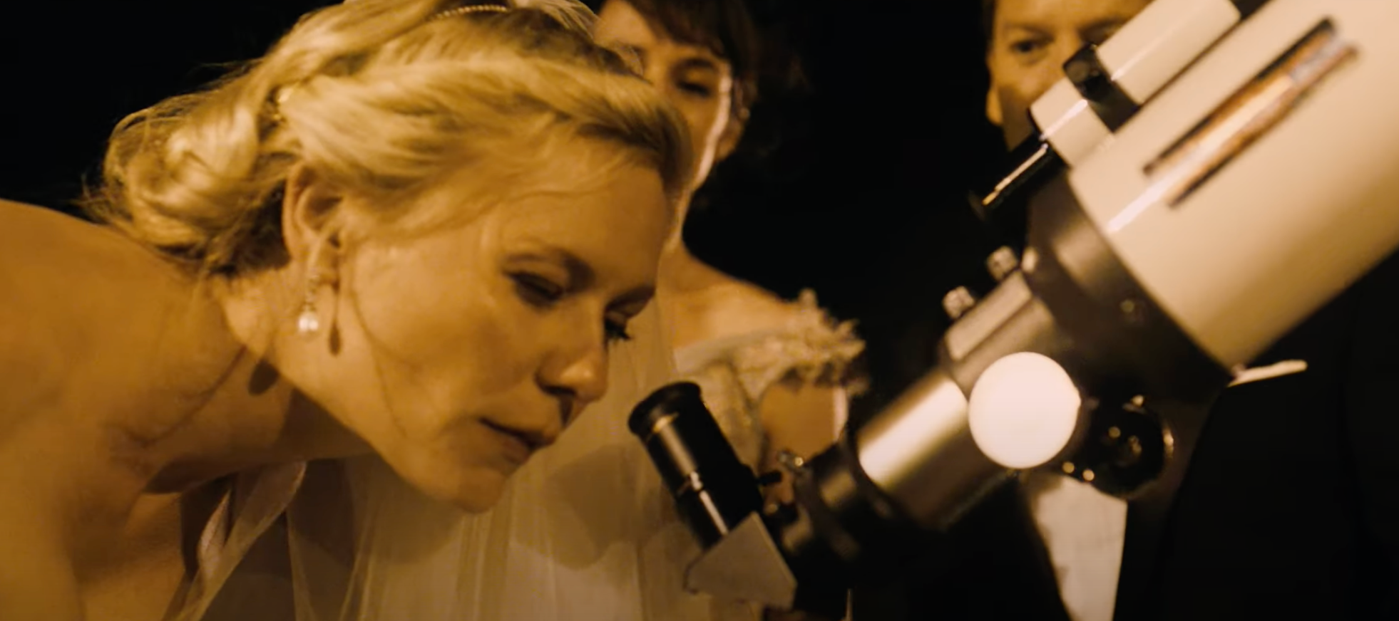 Kirsten Dunst peers into a telescope at night in a scene from &quot;Melancholia&quot;