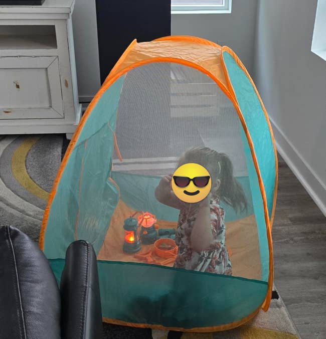 Child successful a play structure with toys, including a glowing lantern and a binocular toy, successful a cozy surviving country setup