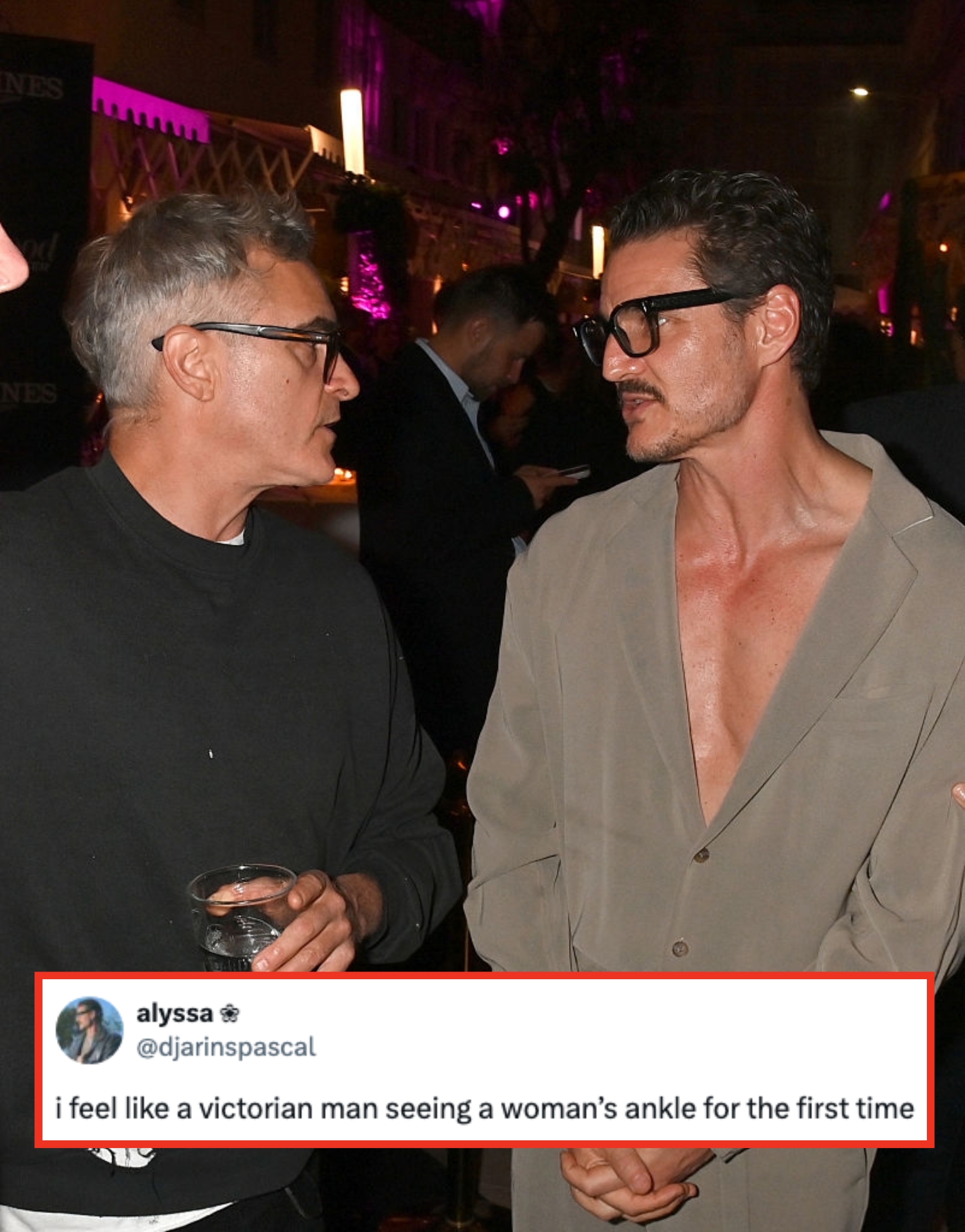 Two people talking at an event. One is wearing glasses and a casual shirt, the other a suit with an open collar, without a tie, also wearing glasses