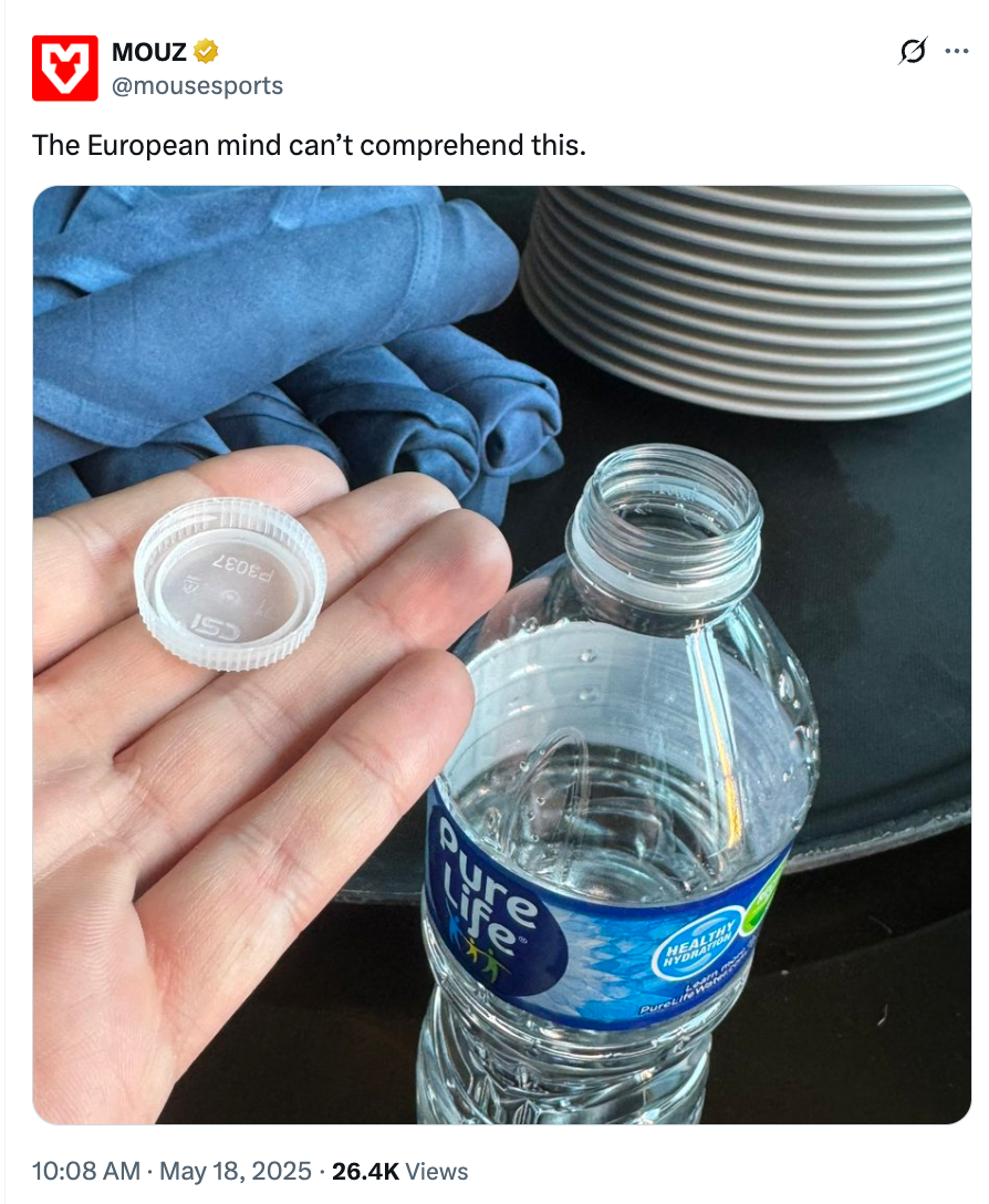 A hand holding a twist-off bottle cap next to an opened water bottle, with stacked plates and cloth in the background