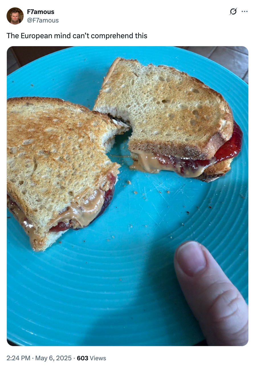 A grilled peanut butter and jelly sandwich is on a blue plate. A thumb is visible at the plate's edge