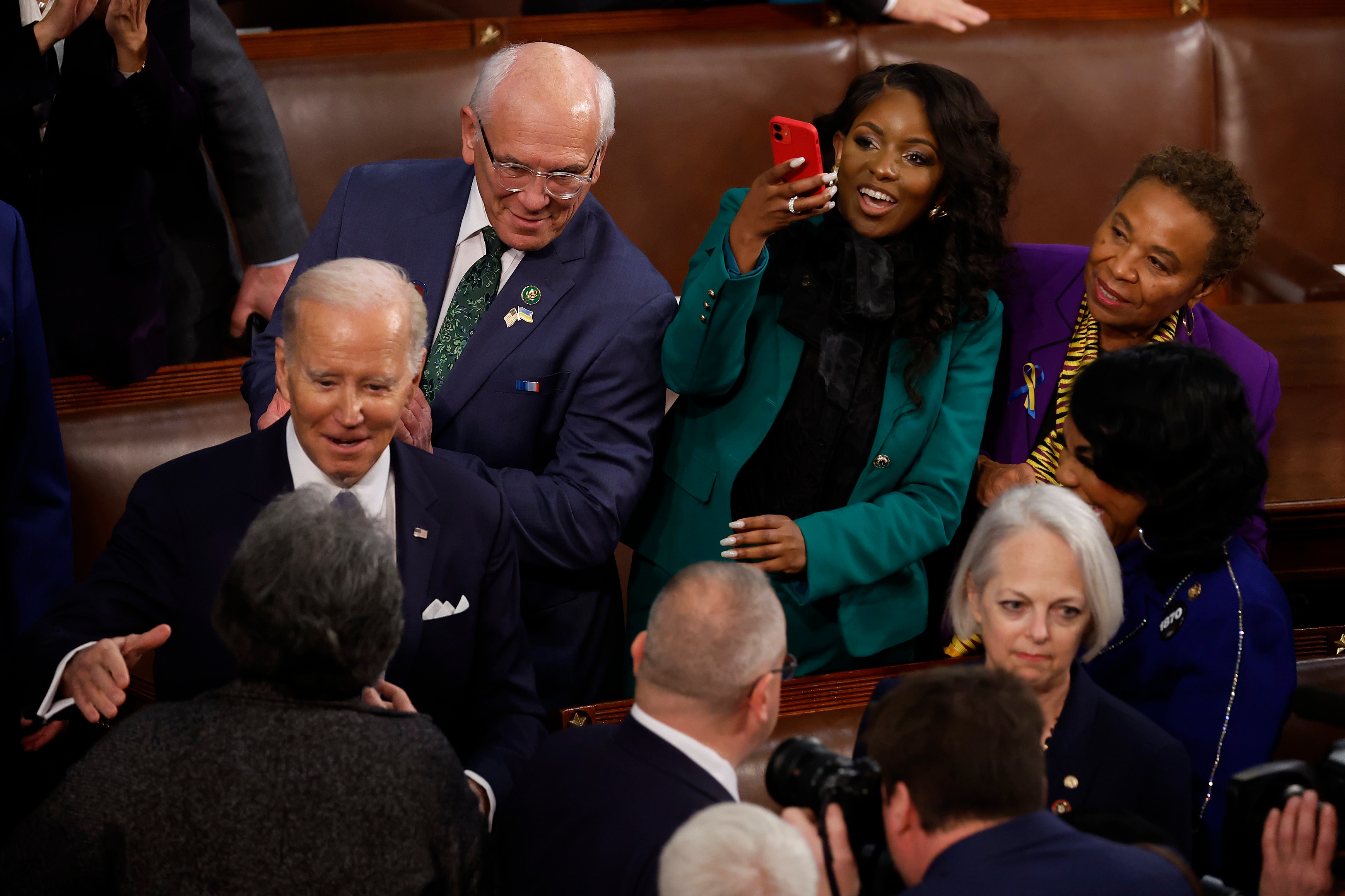 A group of people, including a prominent figure, engage in conversation and photo-taking in a government setting