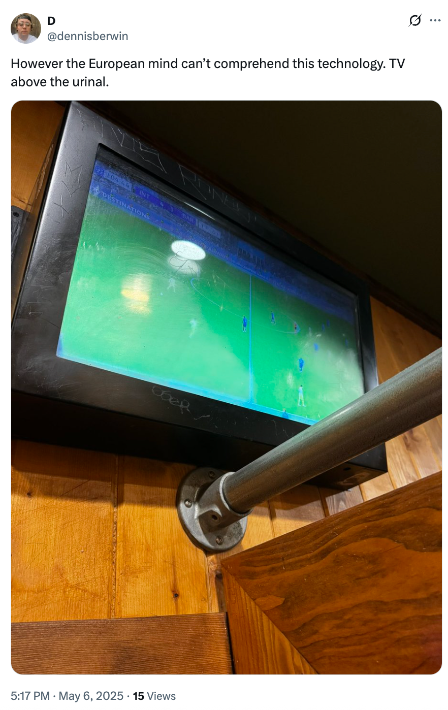 Television screen displaying a soccer match is mounted above a urinal