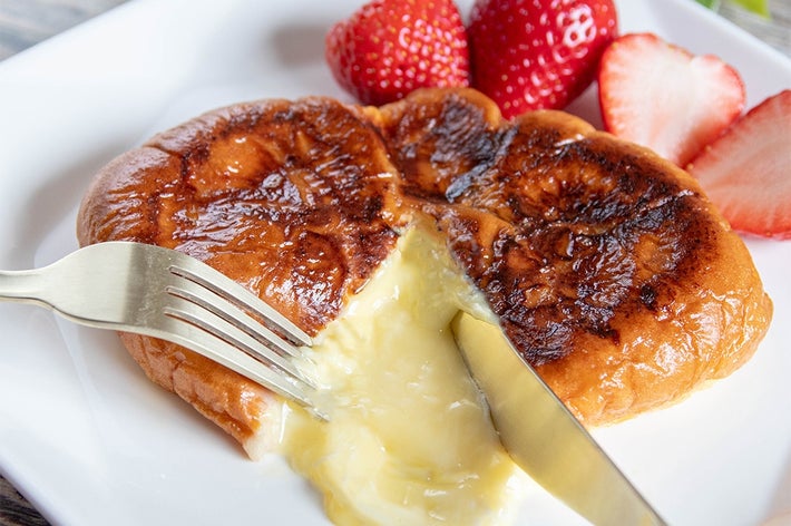焼き色のついたフレンチトーストからクリームが溢れ、いちごが添えられたプレート。