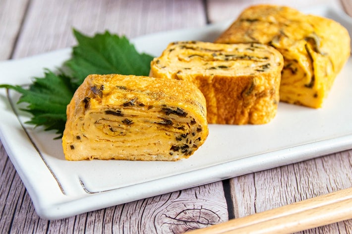 お皿に盛られた、塩昆布が入った卵焼きが4切れ。箸と大葉が添えられている。