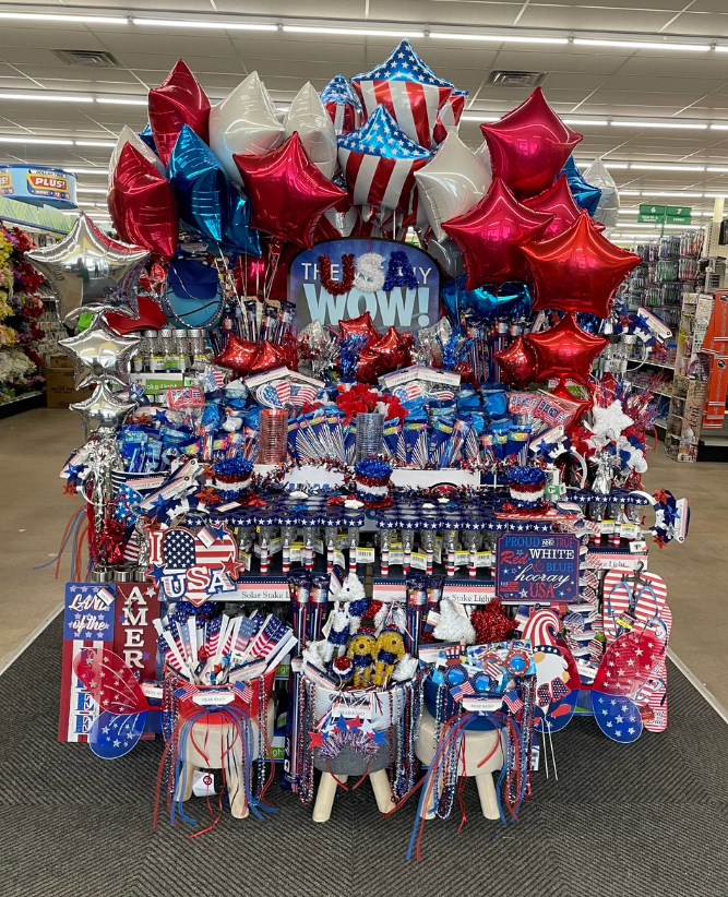 Patriotic July 4th display in a store, featuring themed decorations and items like flags and red, white, and blue balloons