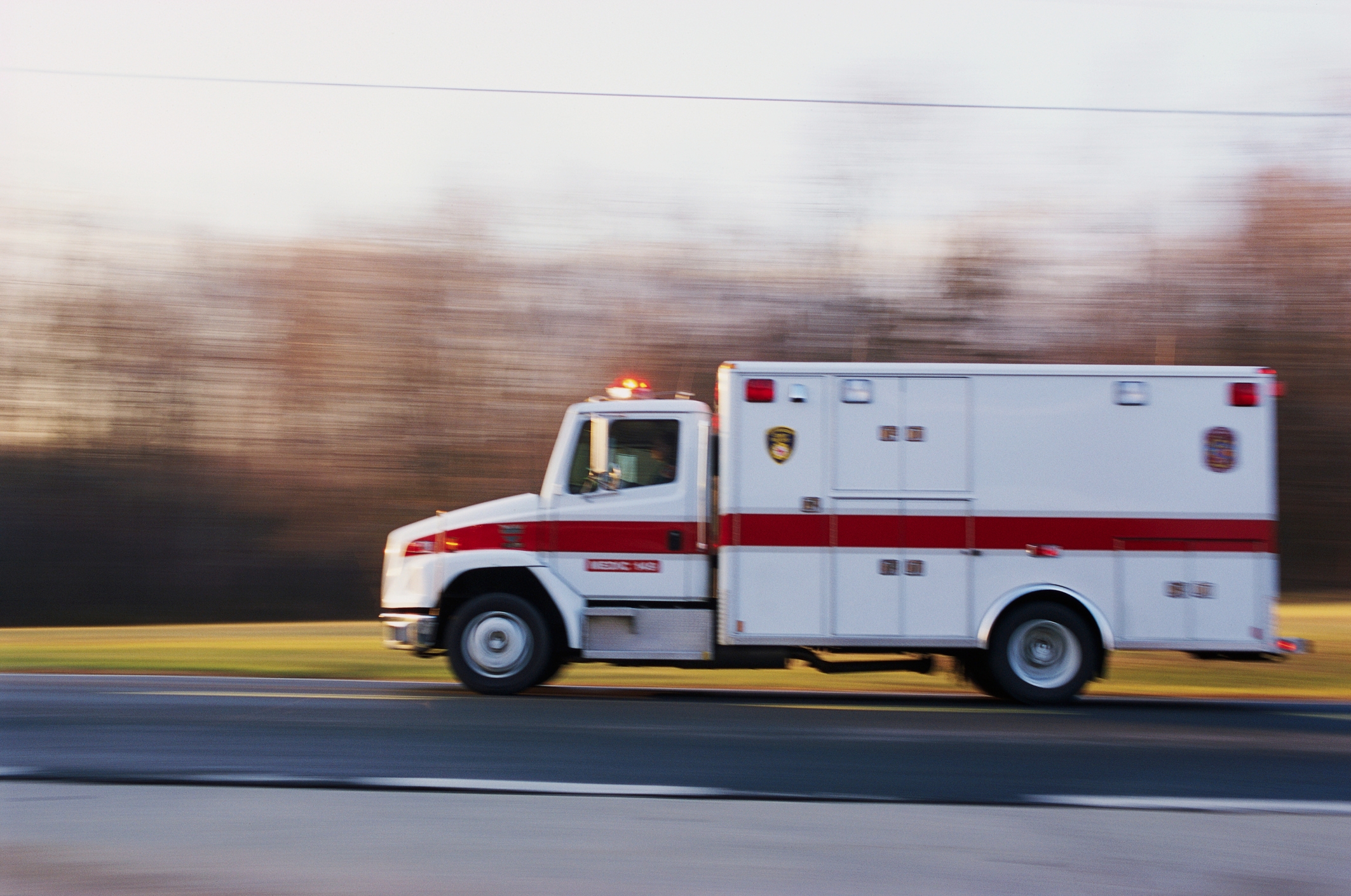 Ambulance speeding on a road with blurred background, indicating urgency