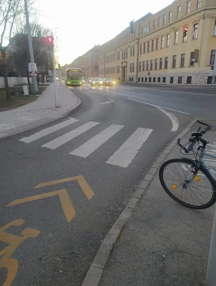 Street view with bike lane, bicycle parked, zebra crossing, and bus approaching on the road