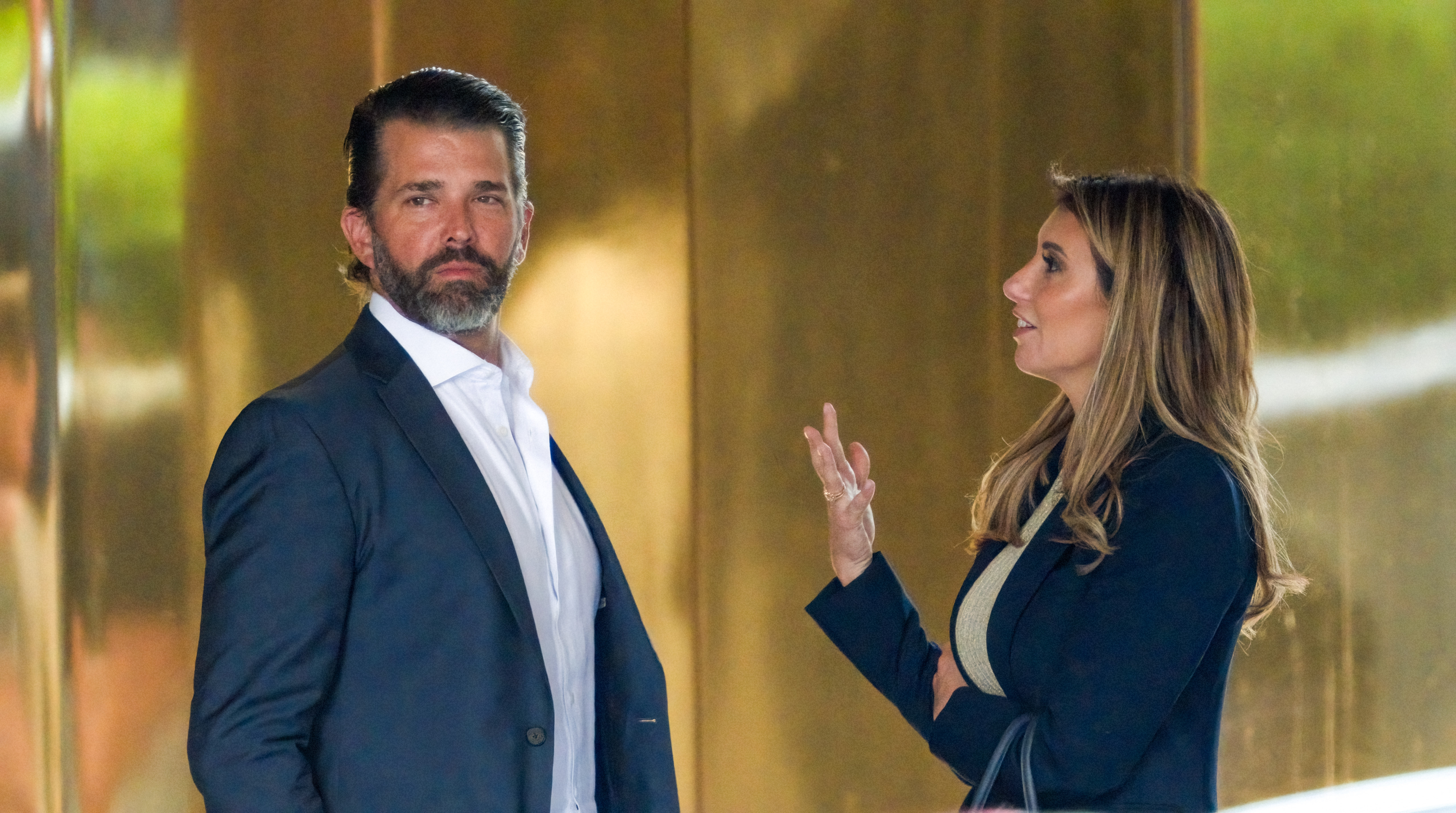 I don’t know who they are, but the man is in a suit and the woman is in business attire having a conversation outdoors