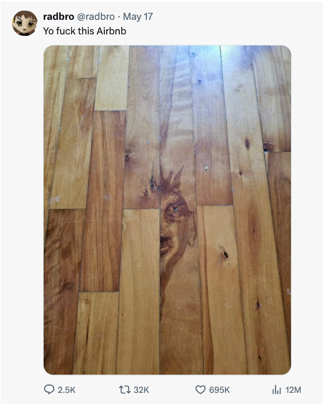 Wooden floor with a pattern resembling a face. The meme caption humorously blames an Airbnb for the eerie design