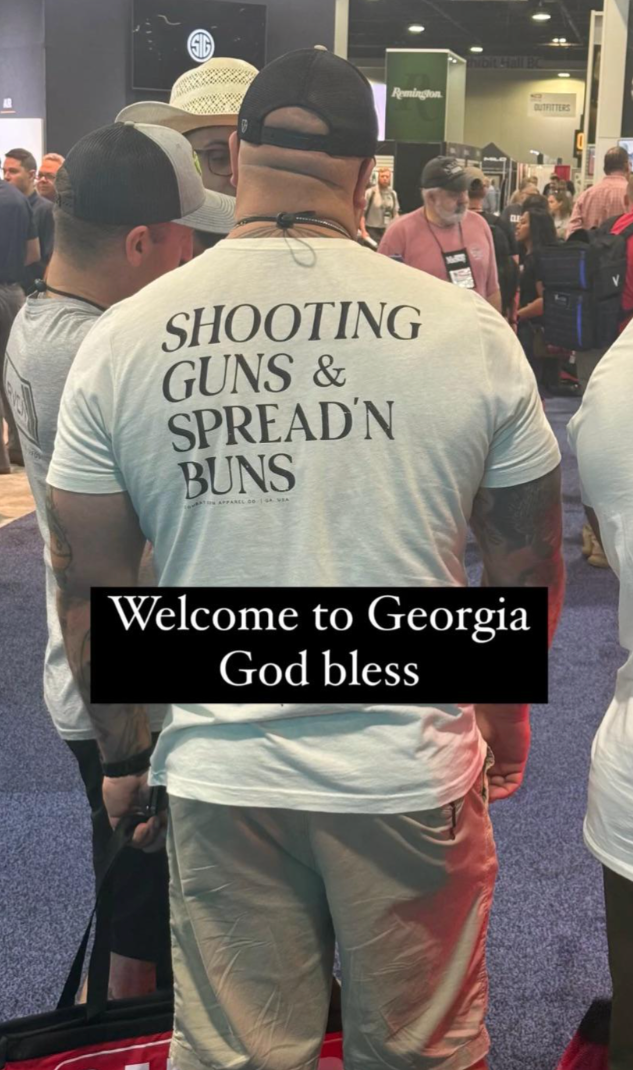 Man in a cap wearing a shirt saying "Shooting Guns & Spread'n Buns" at an event; overlay text reads, "Welcome to Georgia God bless."