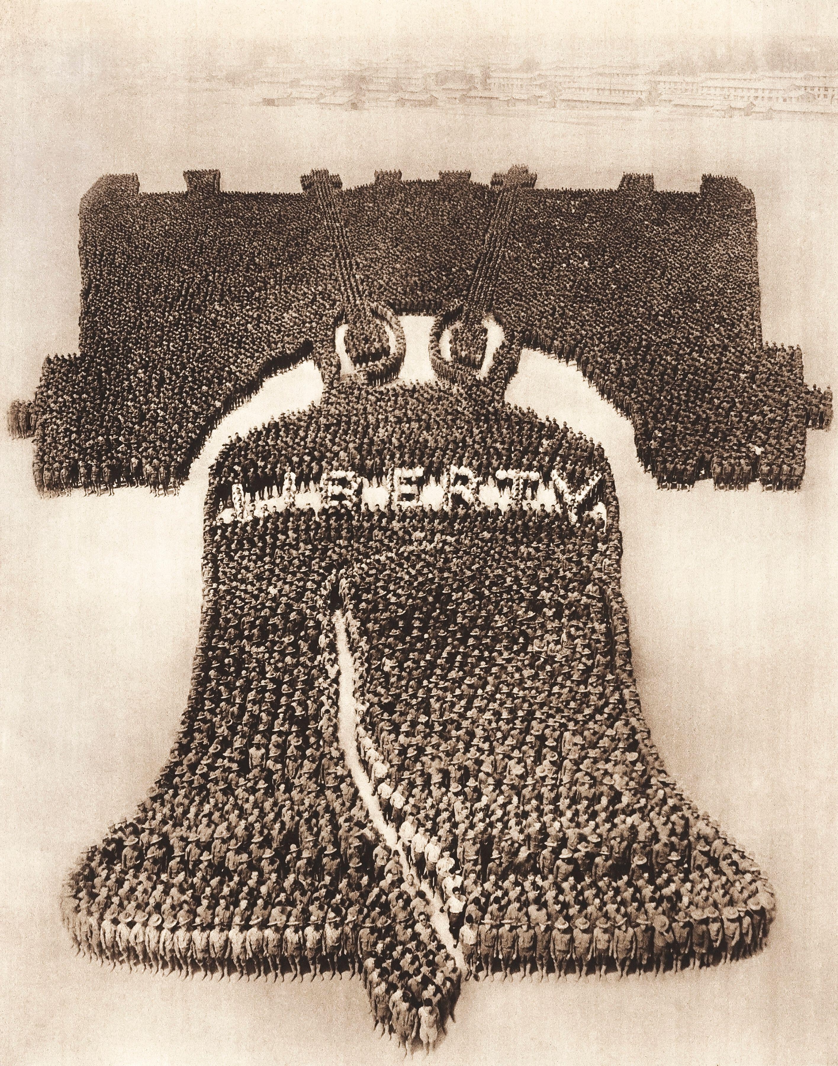 Thousands of people are assembled to form the shape of the Liberty Bell with the word "Liberty" visible in the middle