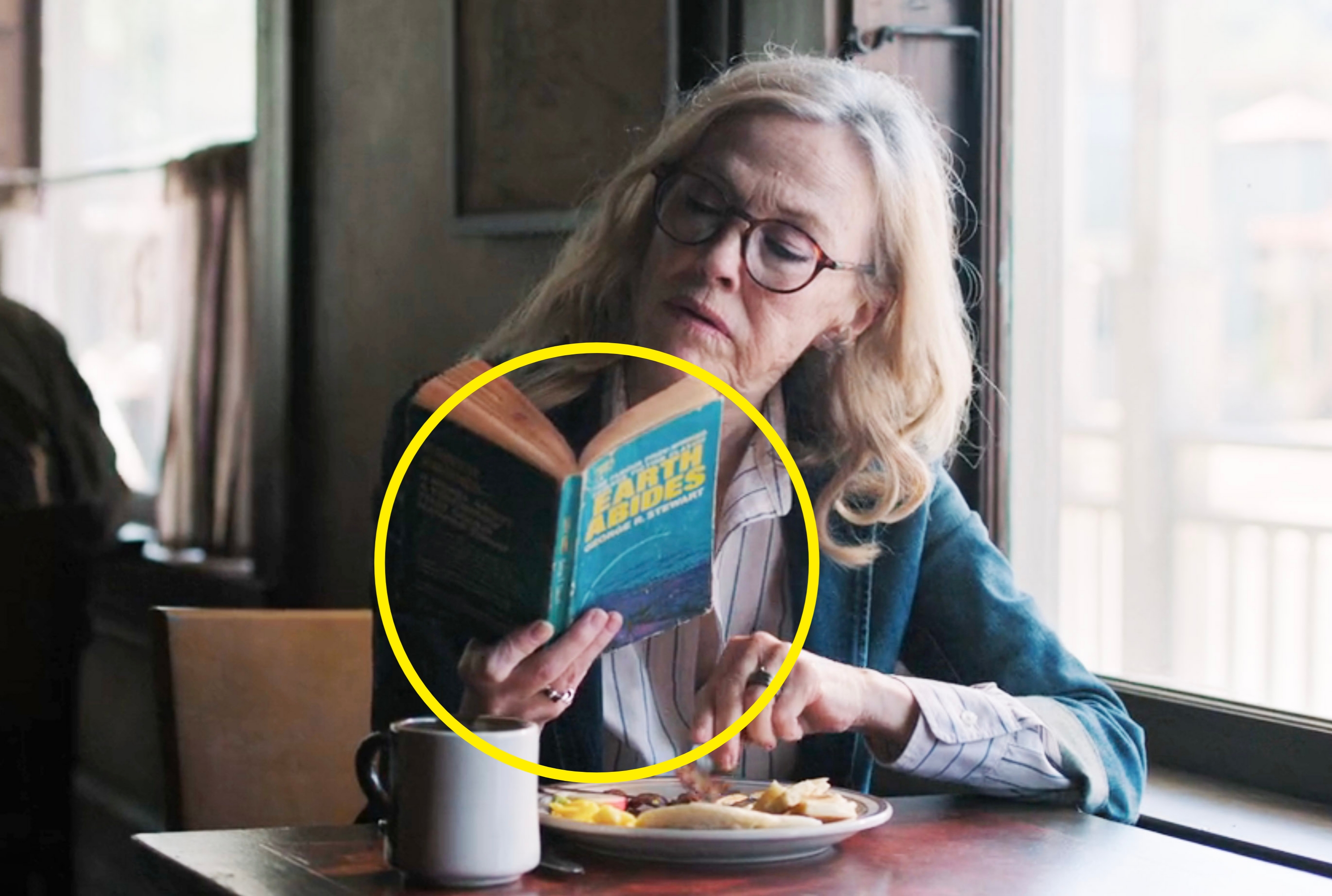 A close-up of Gail reading a book that says, "Earth Abides" on the cover