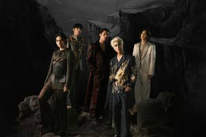 Five people pose dramatically on a rocky landscape, each wearing stylish, diverse outfits ranging from formal suits to bold, artistic designs