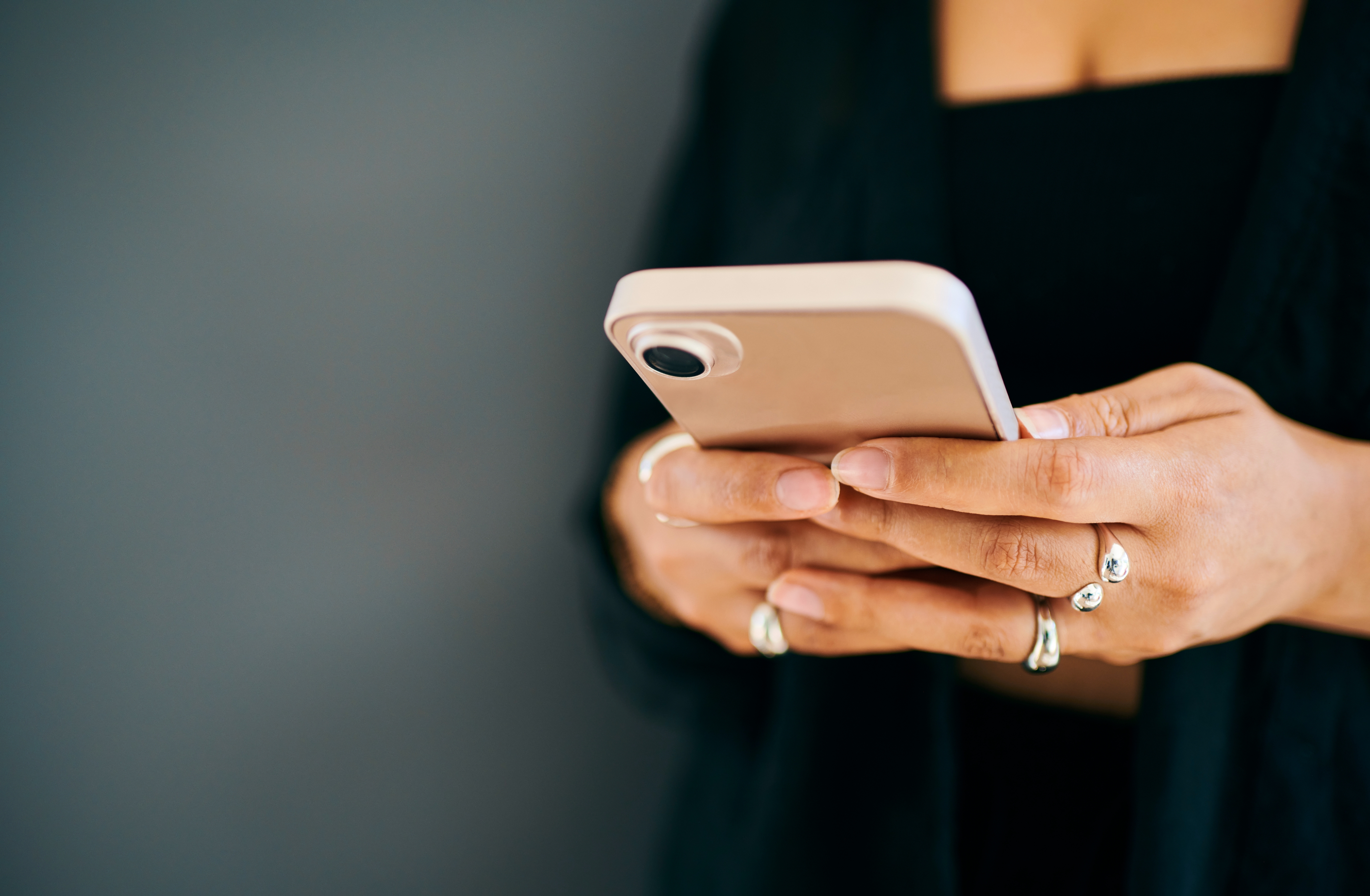Personen som holder en smarttelefon, har på seg ringer på begge hender