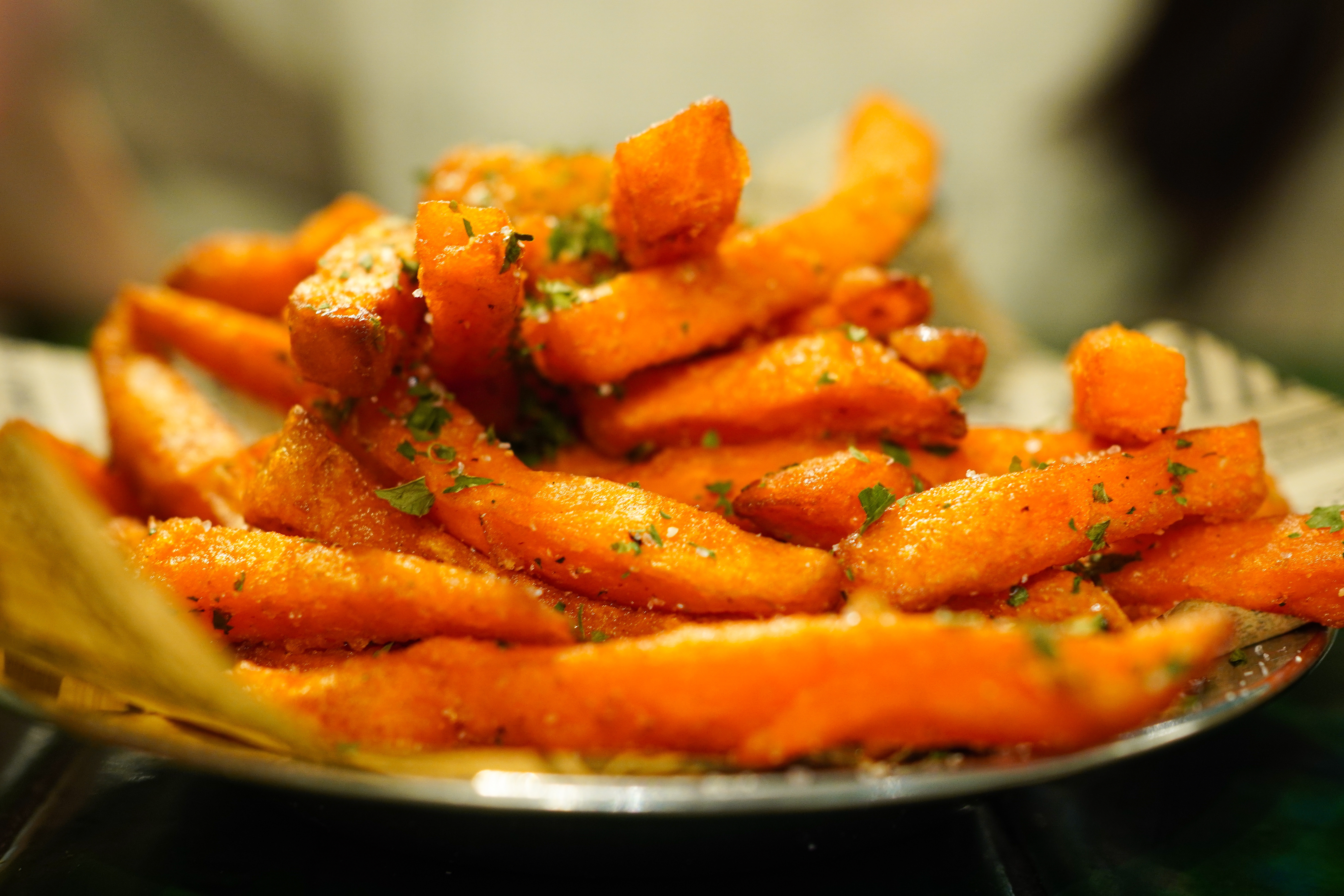 Nærbilde av en tallerken med søtpotet pommes frites krydret med urter