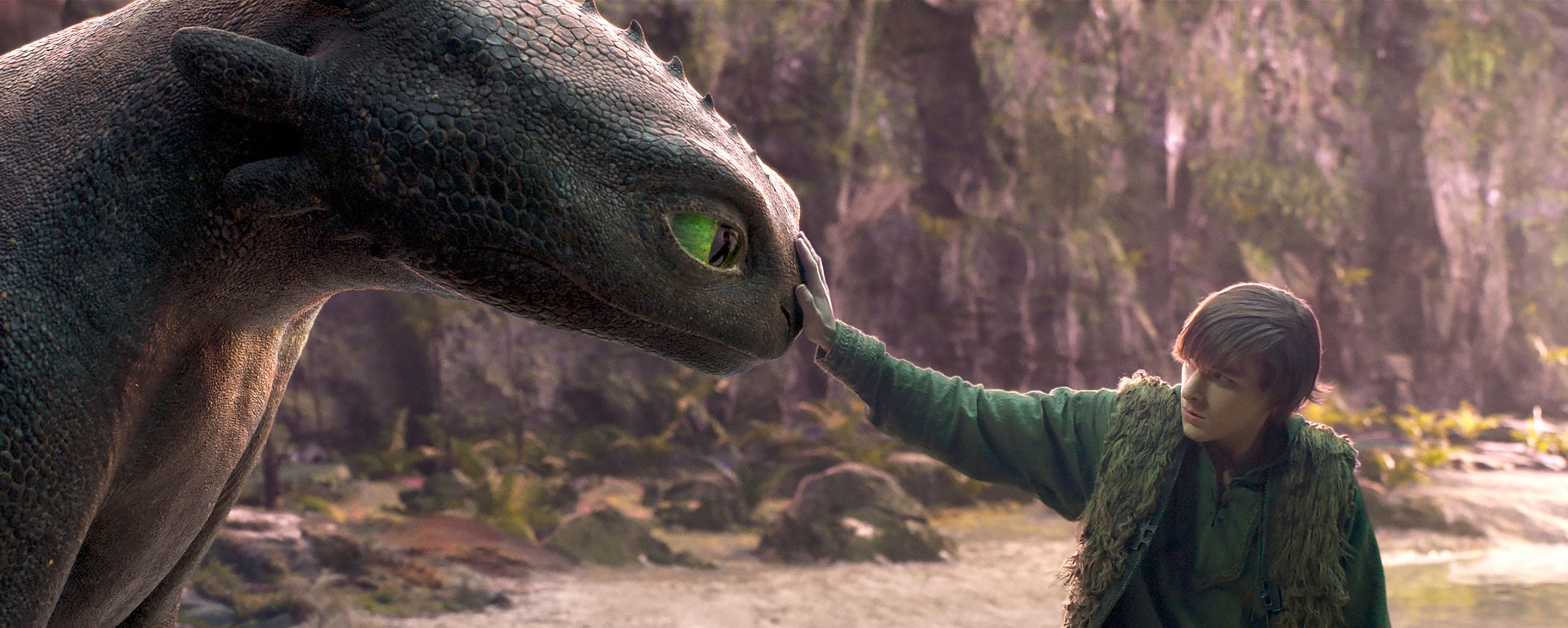 A young man gently touches the snout of a large, dragon-like creature in a forest setting