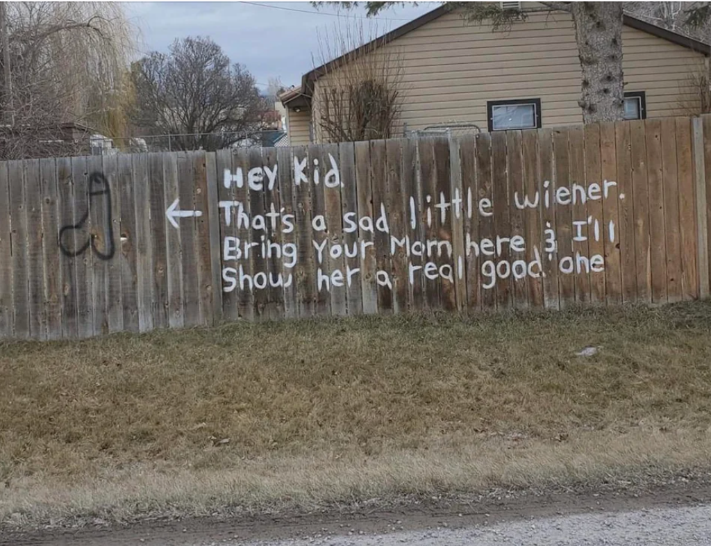 Graffiti on a fence reads: "Hey kid, that's a sad little wiener. Bring your mom here & I'll show her a real good one."
