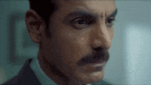 Person with a mustache looks intently into the distance, appearing thoughtful