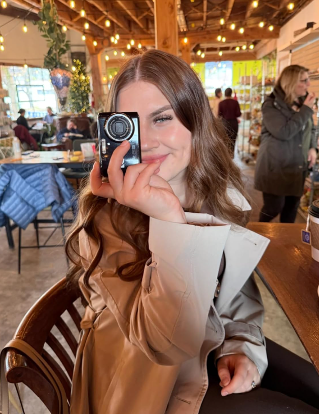 reviewer smiles portion    playfully holding a tiny  camera