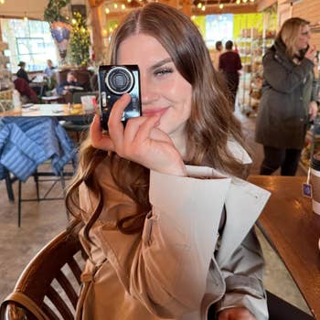 reviewer smiles portion playfully holding a tiny camera