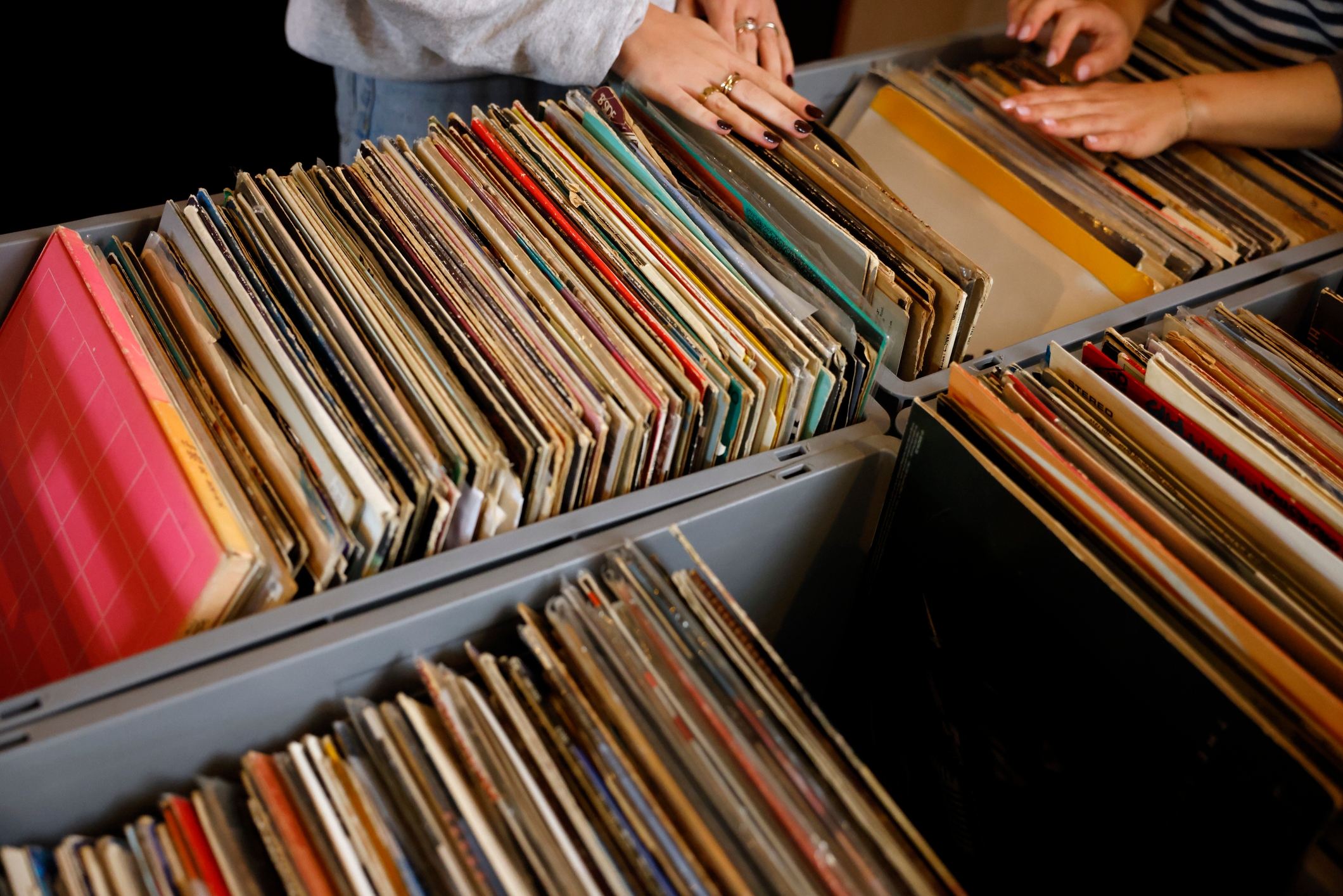 Hands browsing through crates of vinyl records, suggesting a vintage or retro theme