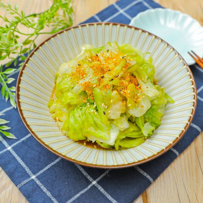 皿に盛られたレタスのサラダ。ごまやスパイスがトッピングされ、さっぱりとした印象。