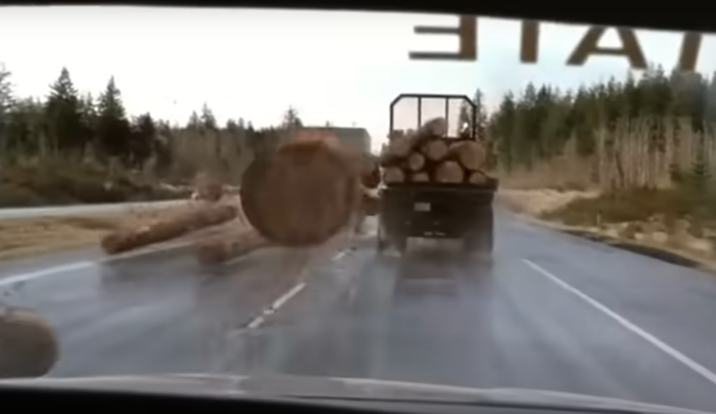 A log hurtling off a logging truck toward's a car windshield