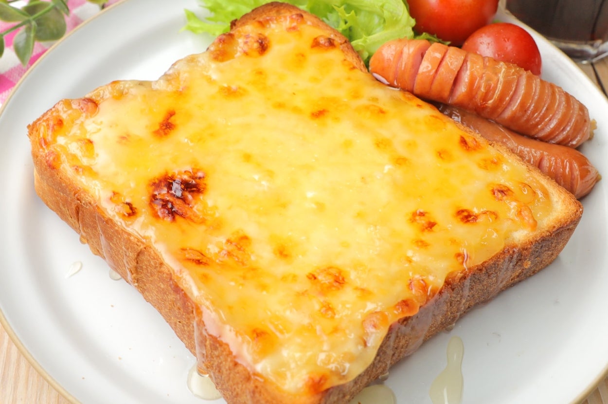 トーストに溶けたチーズ、ソーセージ、レタス、トマトが添えられた朝食プレート。