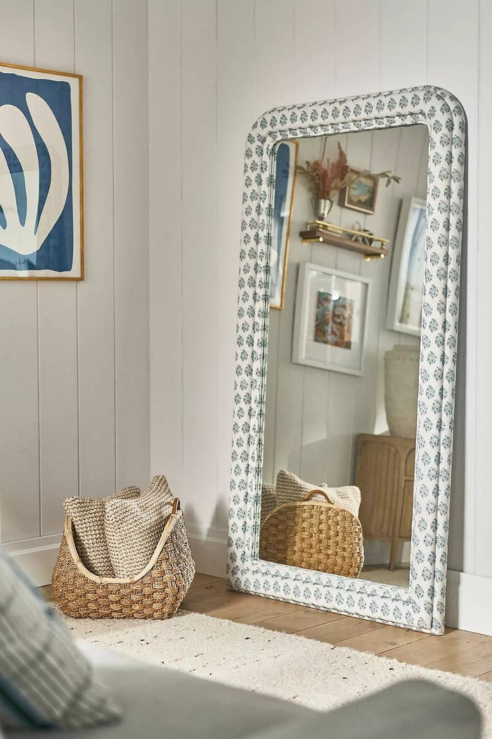 Decorative level  reflector  with patterned frame, adjacent  to a woven handbasket  with blankets, successful  a modern, stylish room