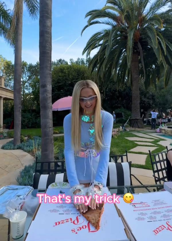 Paris Hilton holding a pizza slice down onto a pizza box with text overlay reading "That's my trick"