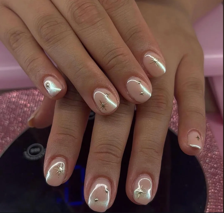 Hands with manicured short nails featuring a glossy finish and star-themed nail art on each finger