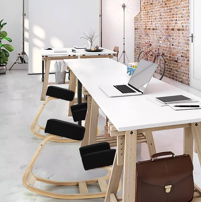 Modern bureau abstraction with laptops connected achromatic desks, ergonomic rocking chairs, and a briefcase connected the floor. Brick partition and decor successful the background