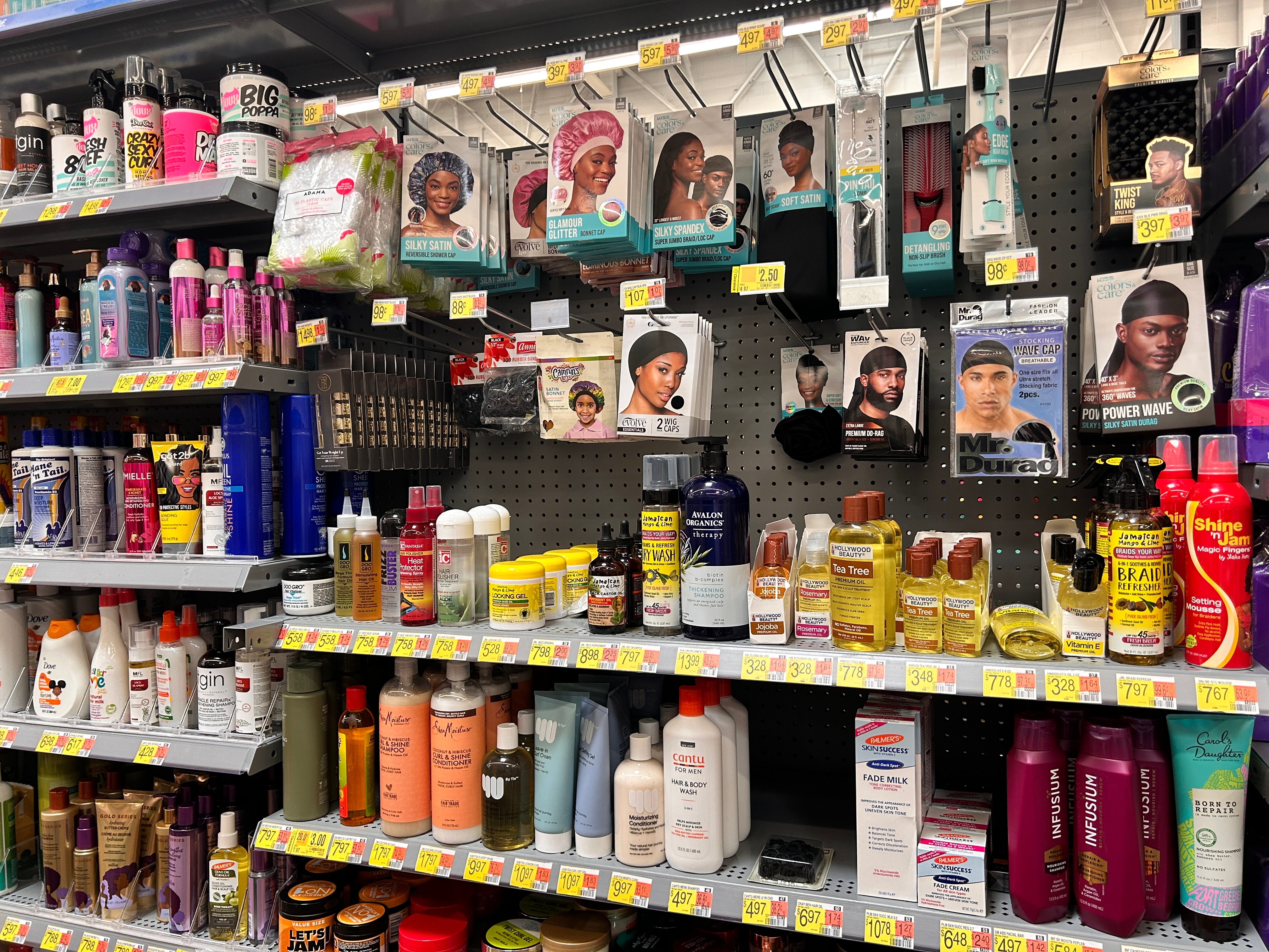 Store shelf with various hair care products including shampoos, conditioners, oils, and hair treatments in different packaging