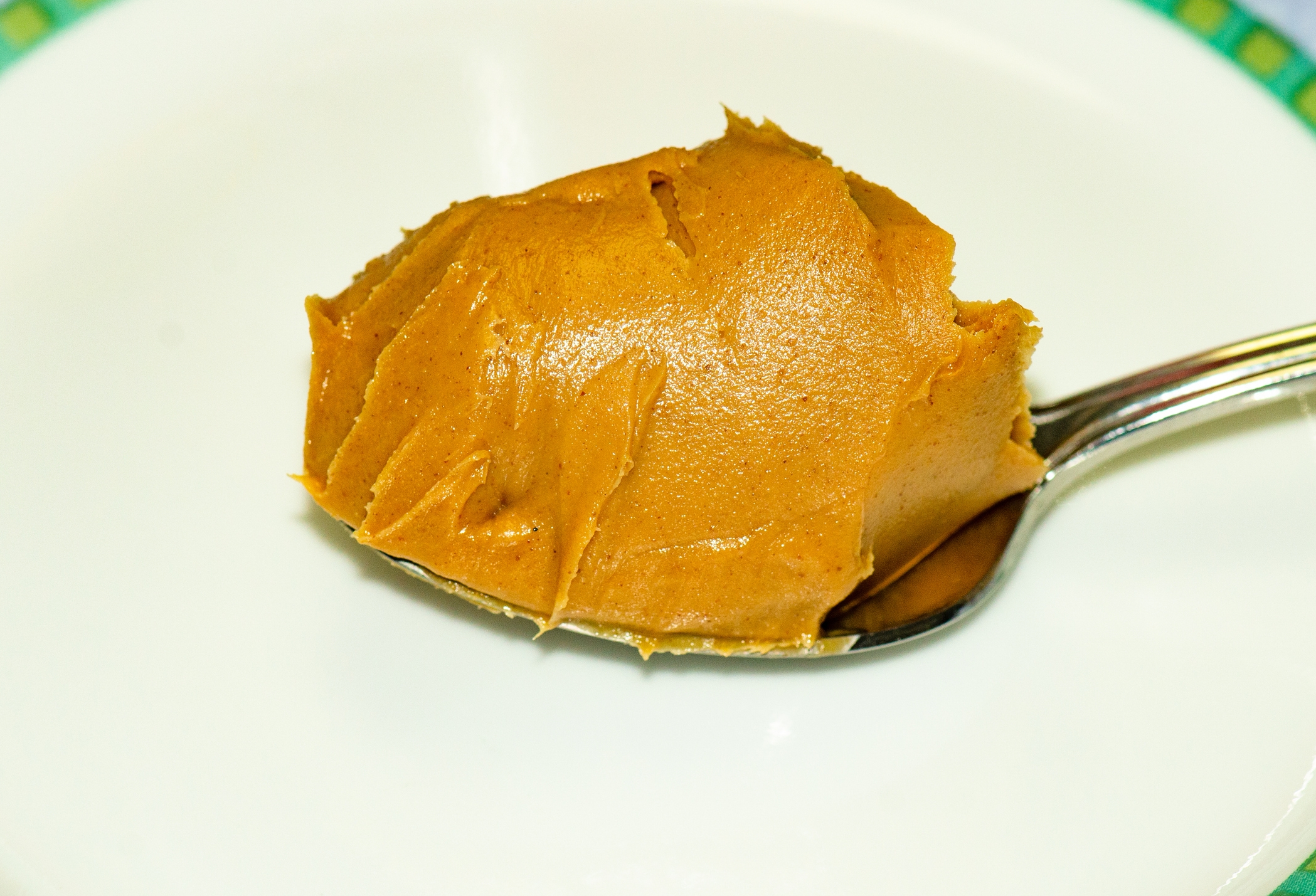 A spoonful of creamy peanut butter rests on a white plate