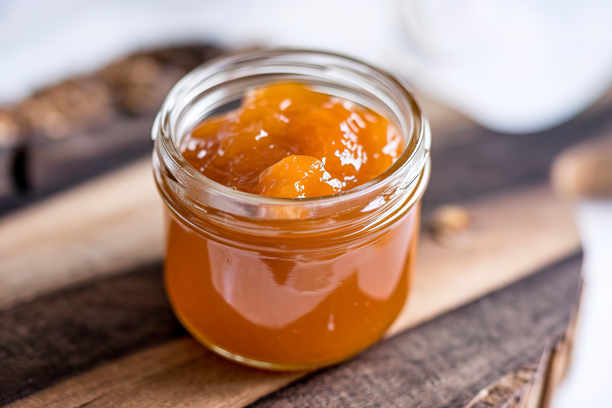 Jar of orange marmalade on a wooden board