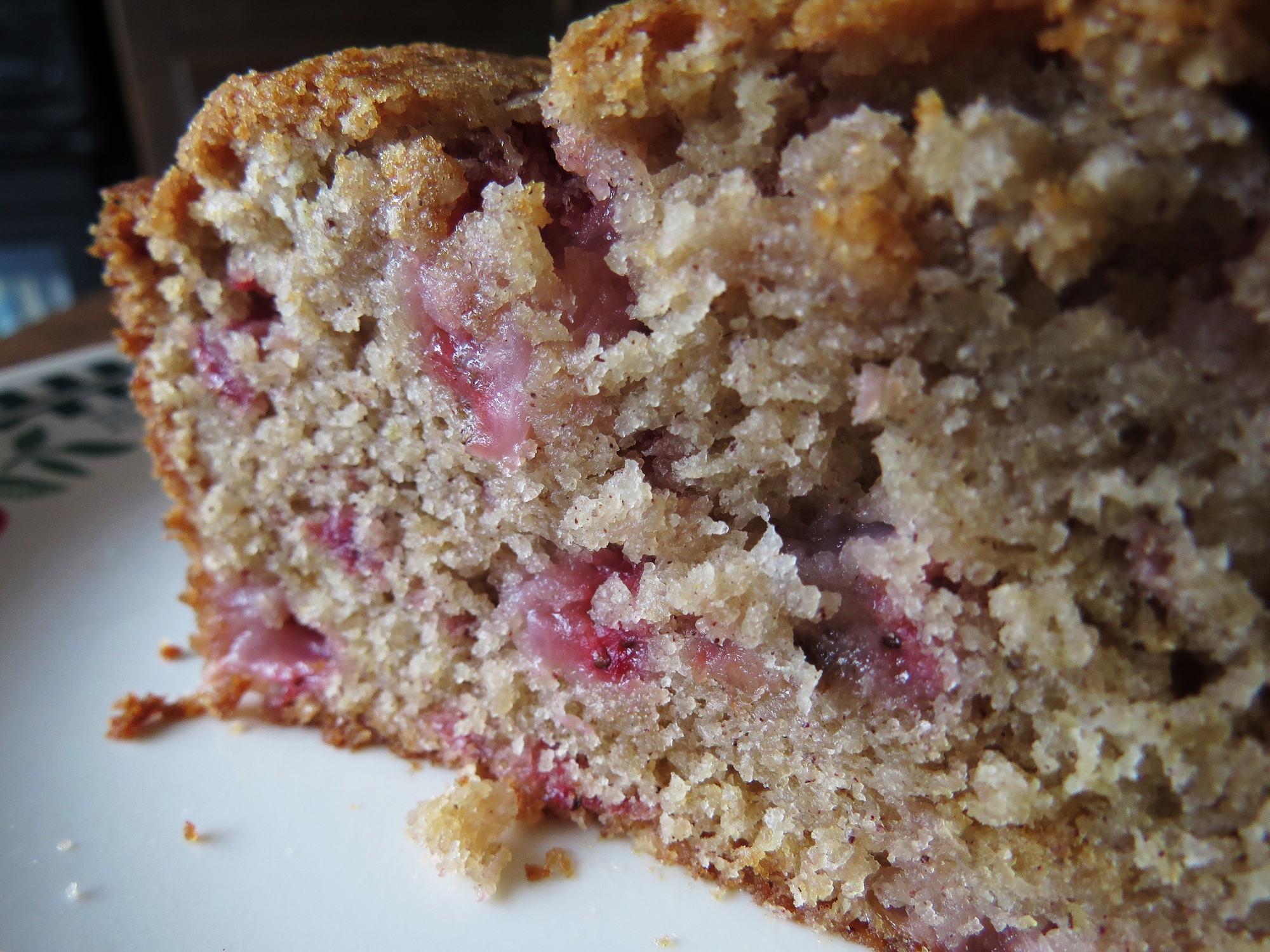 Close-up of a slice of homemade bread with visible berries and a crumbly texture