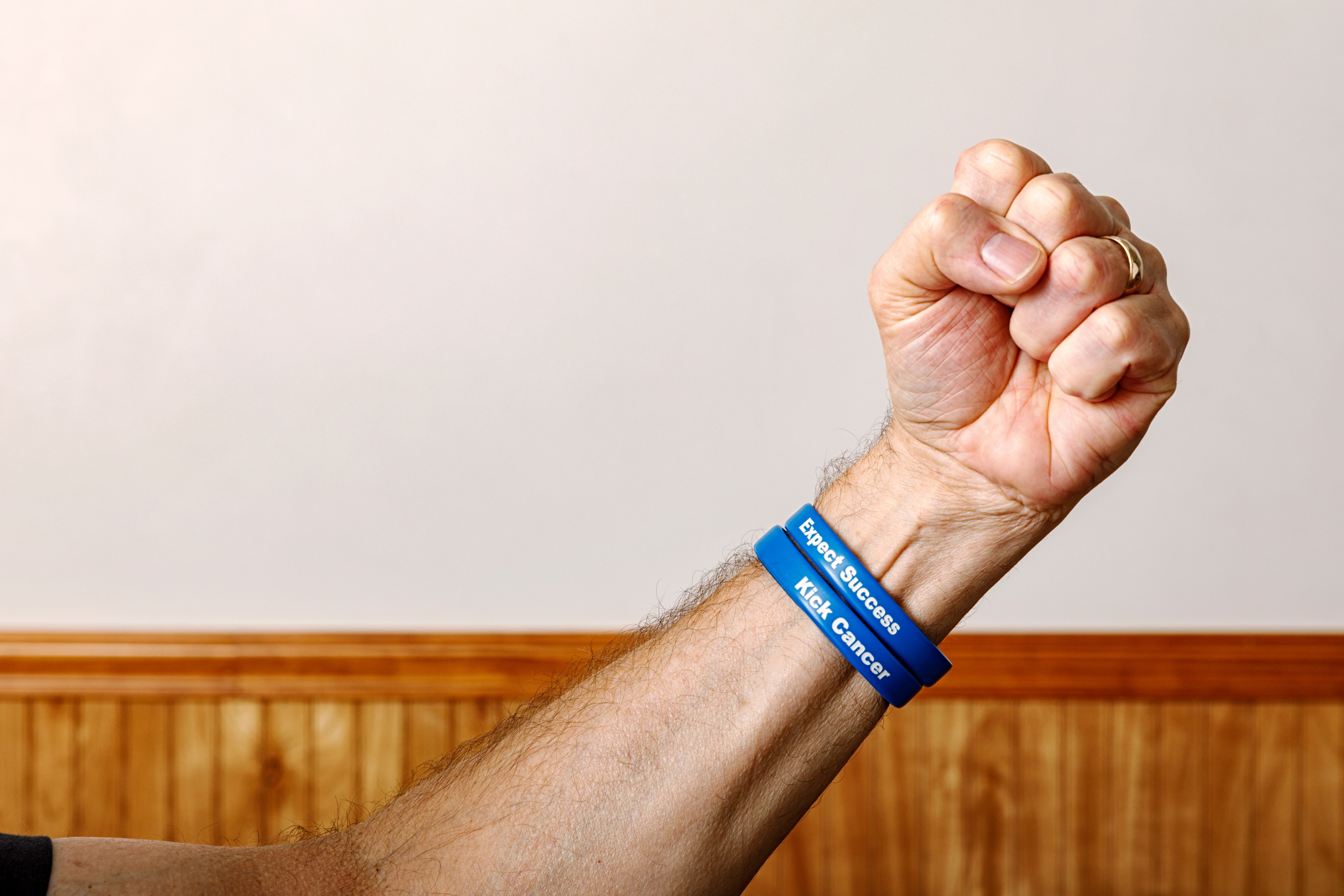 A raised fist wearing two blue wristbands with motivational phrases