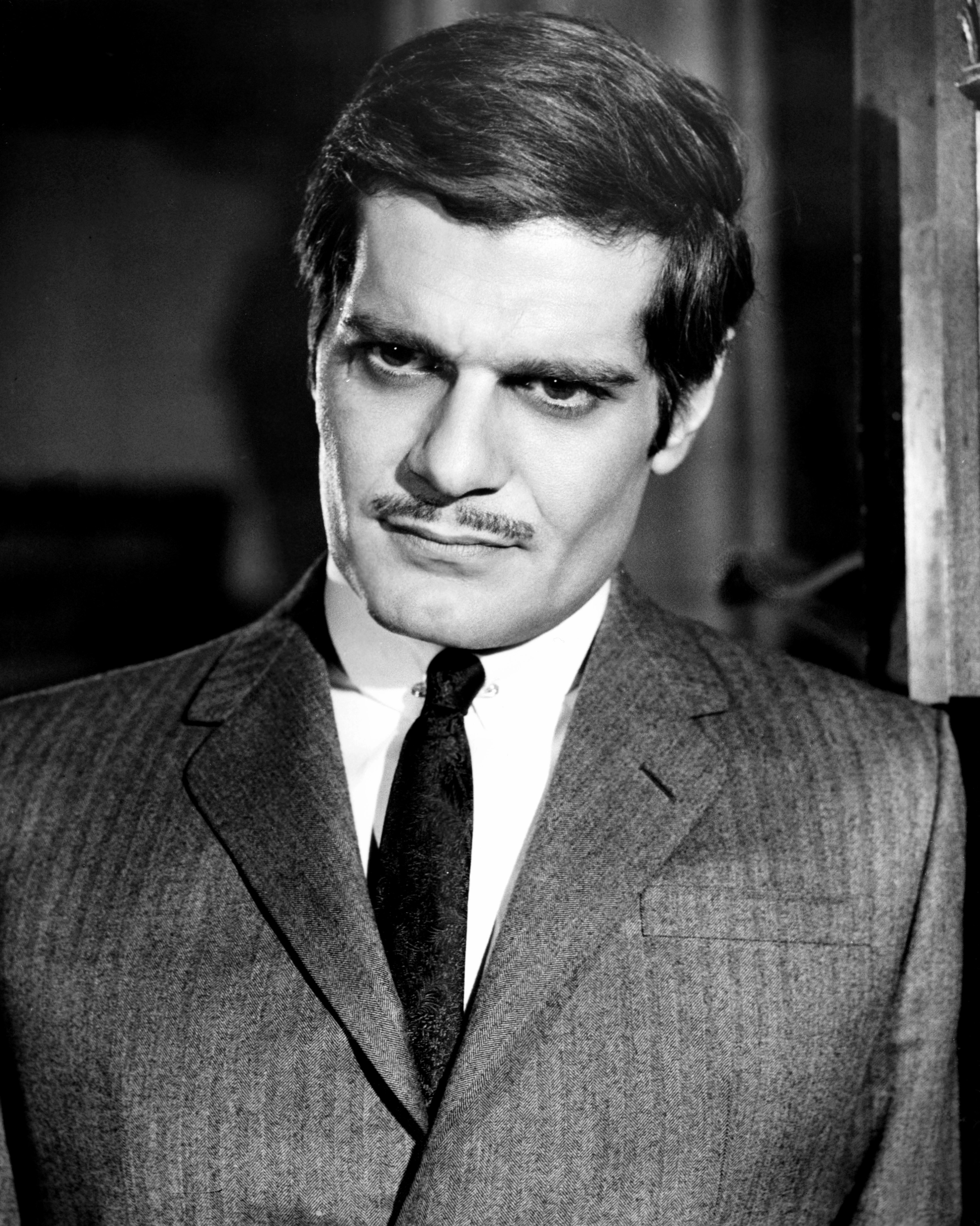 Actor posing in a classic tailored suit with a serious expression, showcasing a mid-20th century style