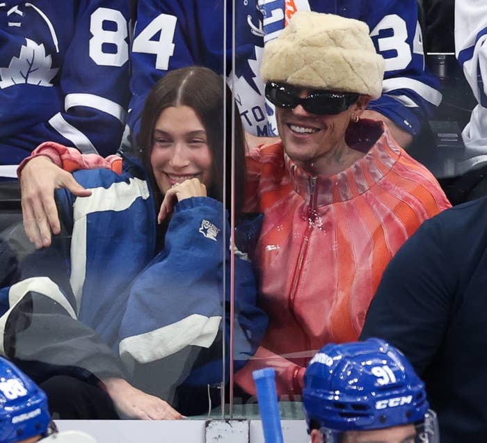 Hockey players connected seat during a game; radical successful suits nearby. Fans successful squad jerseys ticker from down the glass, showing excitement and engagement