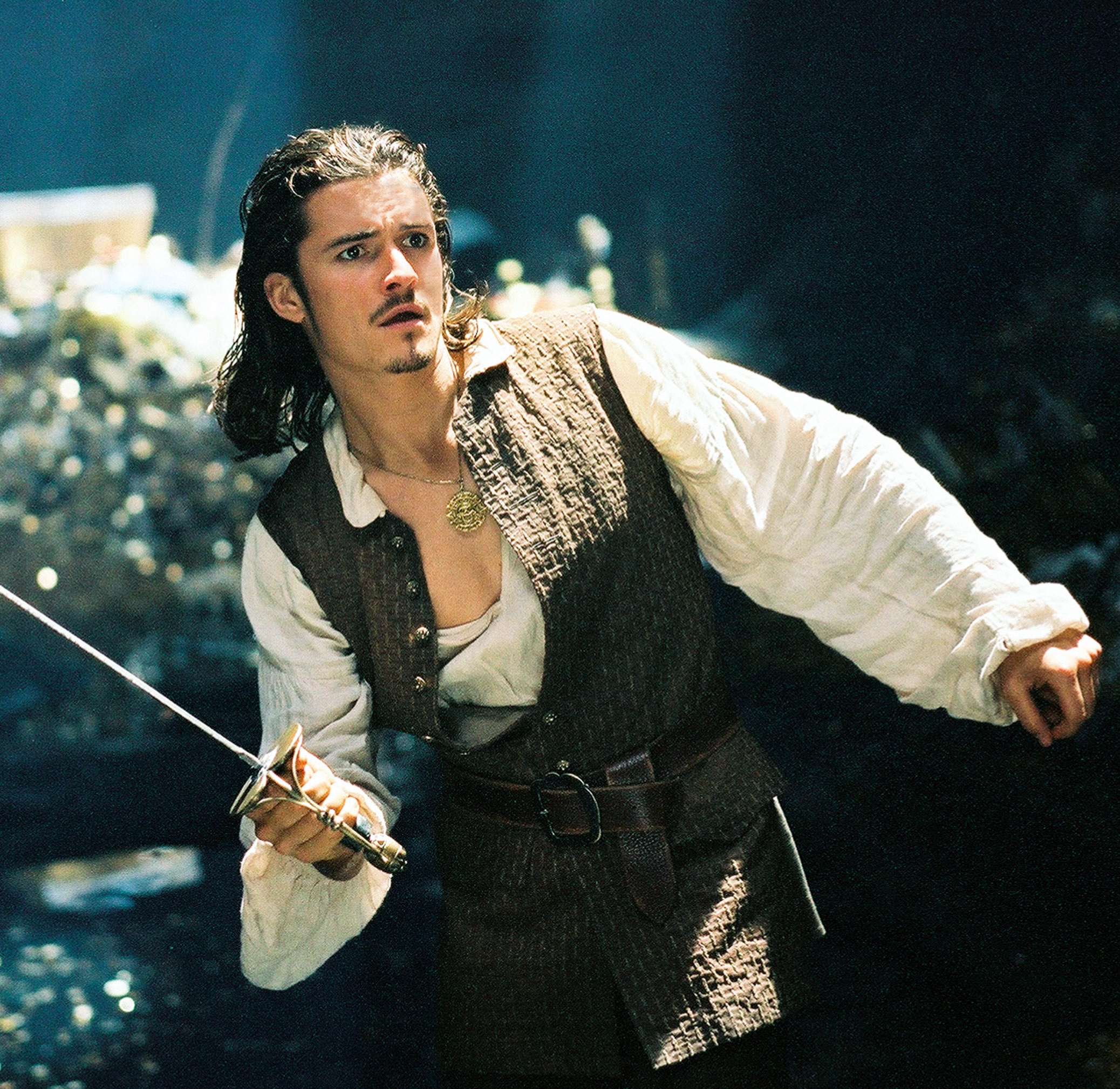 Actor in medieval-style outfit holds a sword, appearing ready for action in a dramatic scene setting