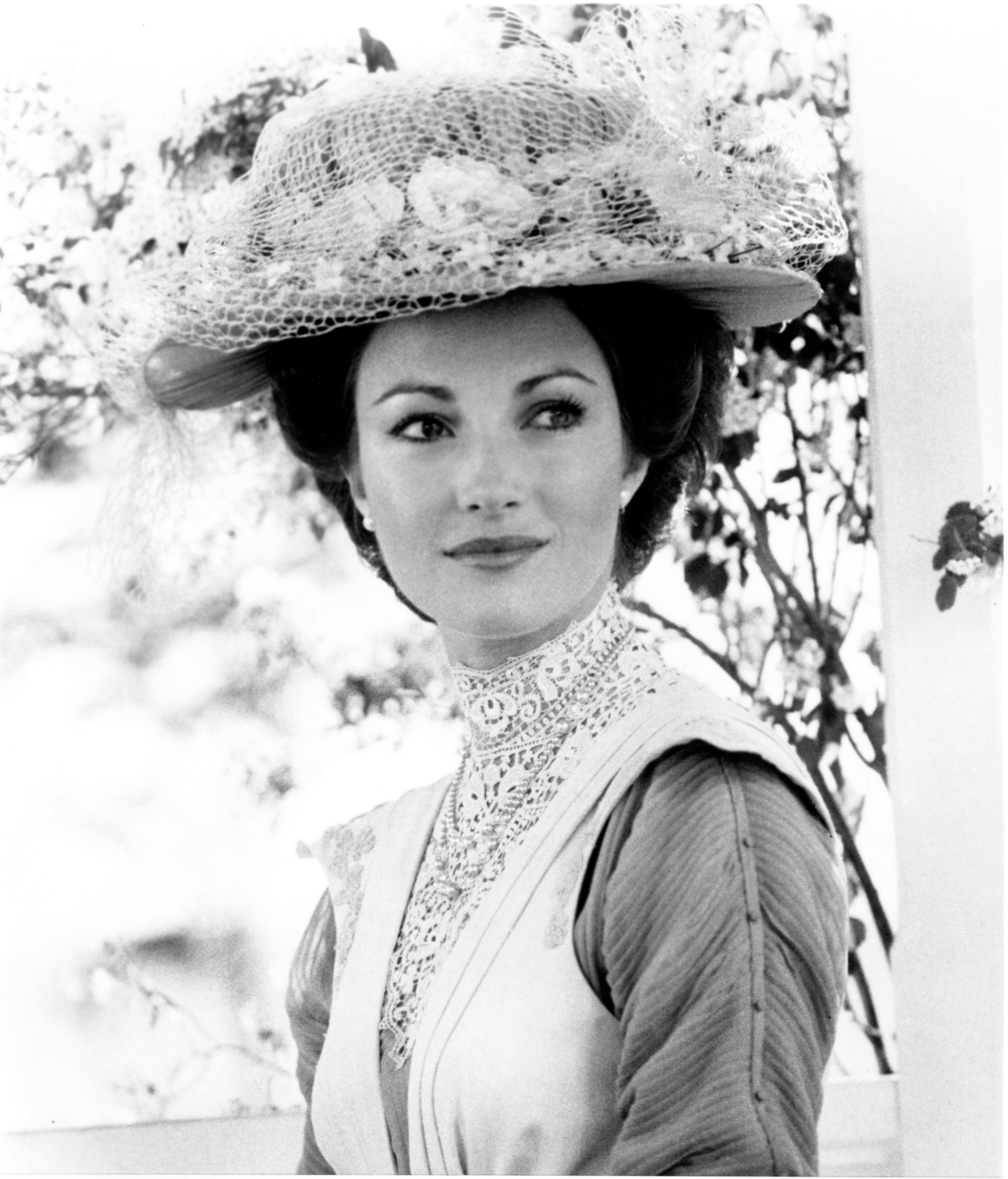 Person in Edwardian-style clothing wearing a lace hat, looking off to the side with a serene expression