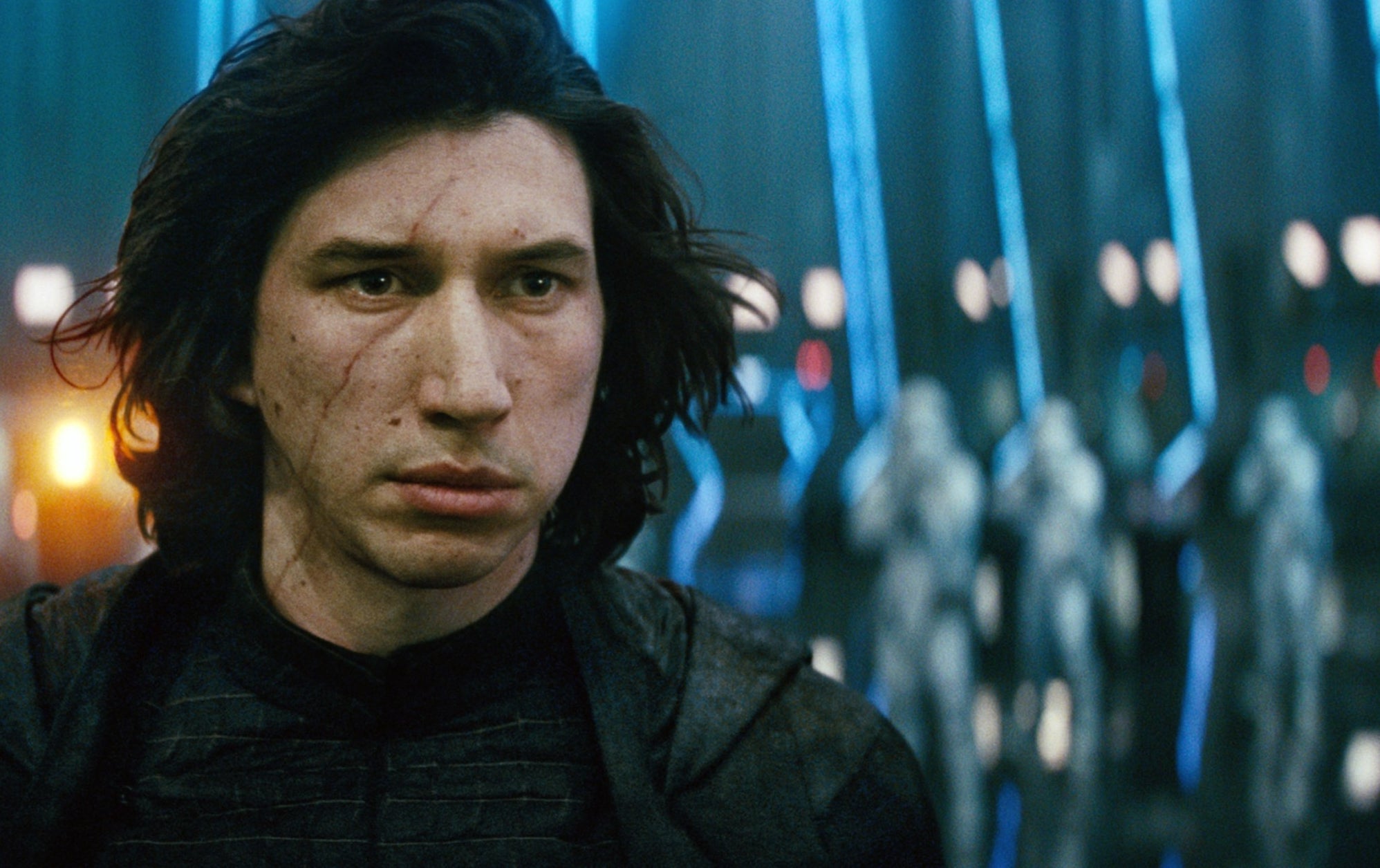 A character, wearing dark attire and looking intense, stands in a sci-fi setting with futuristic blue lighting and figures in the background